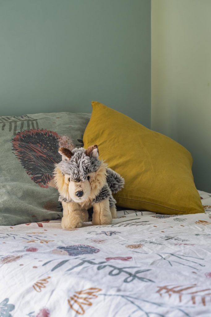 chambre enfant garçon vert papier peint palmier inspiration balinaise voilages ocre aménagement chambre garçon rangement jouets étagères déco figurines peluche lit enfant