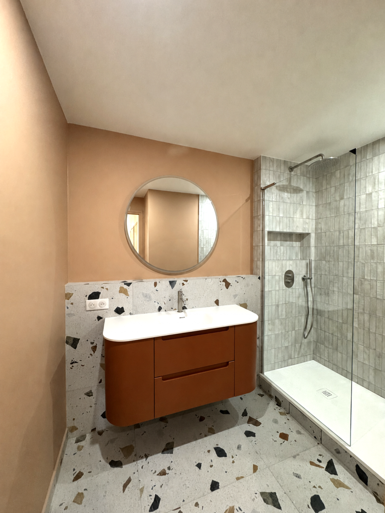Salle d'eau colorée. Meuble vasque arrondi terracotta. Plan vasque intégré. Niche dans la douche. Robinetterie encastrée. Finition haut de gamme. TERRAZZO moderne. Salle d'eau contemporaine. Rénovation total appartement. Transformation salle d'eau